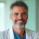 Primo piano del Dott. Marco Rossi, medico generico italiano esperto in prevenzione, che sorride con professionalità e gentilezza